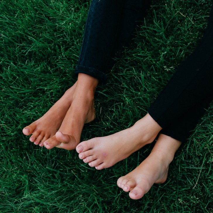 Two pairs of feet crossed on the grass